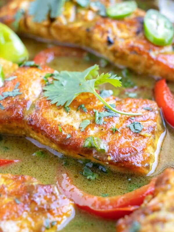 A close-up of a salmon fillet in a coconut milk green curry sauce made with lime juice and curry powder.