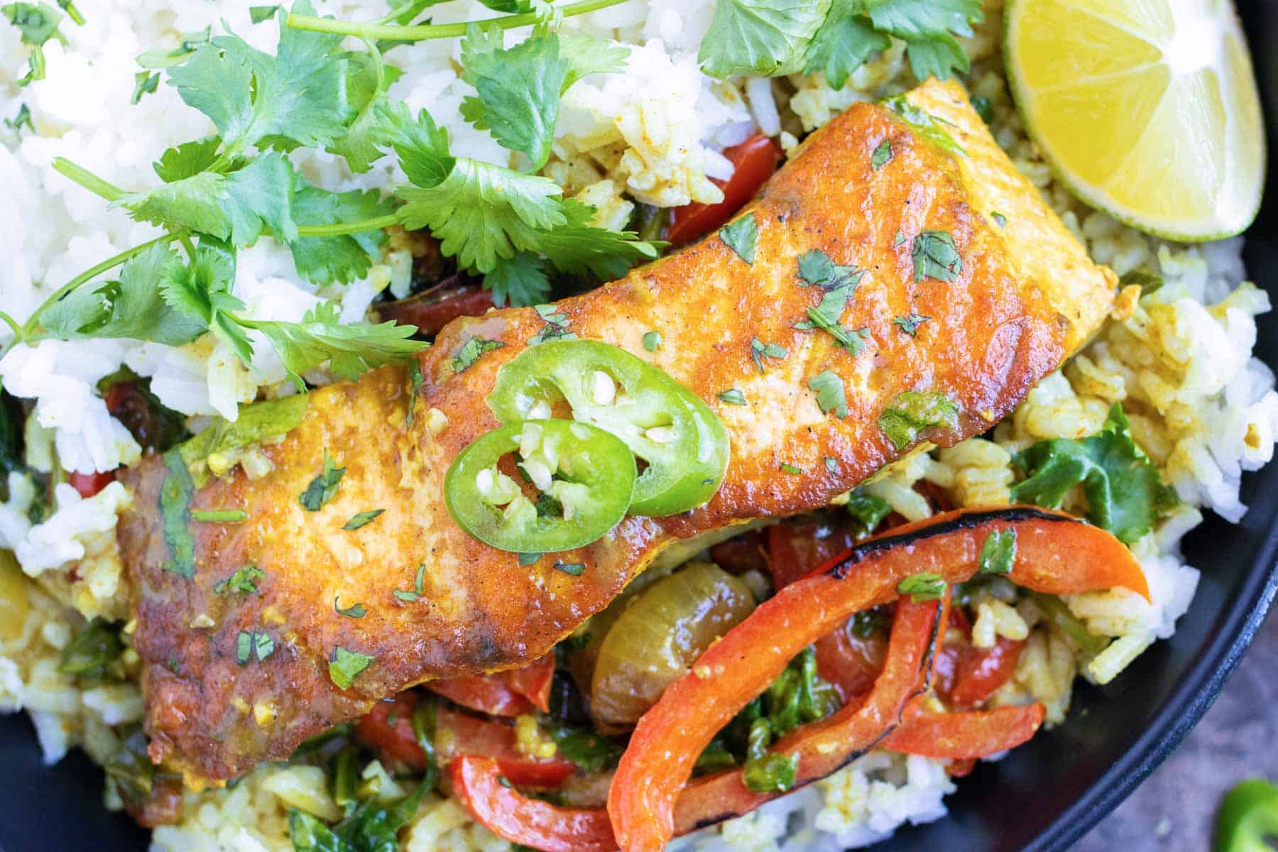 Coconut curry salmon served over rice in a bowl with lime and cilantro.
