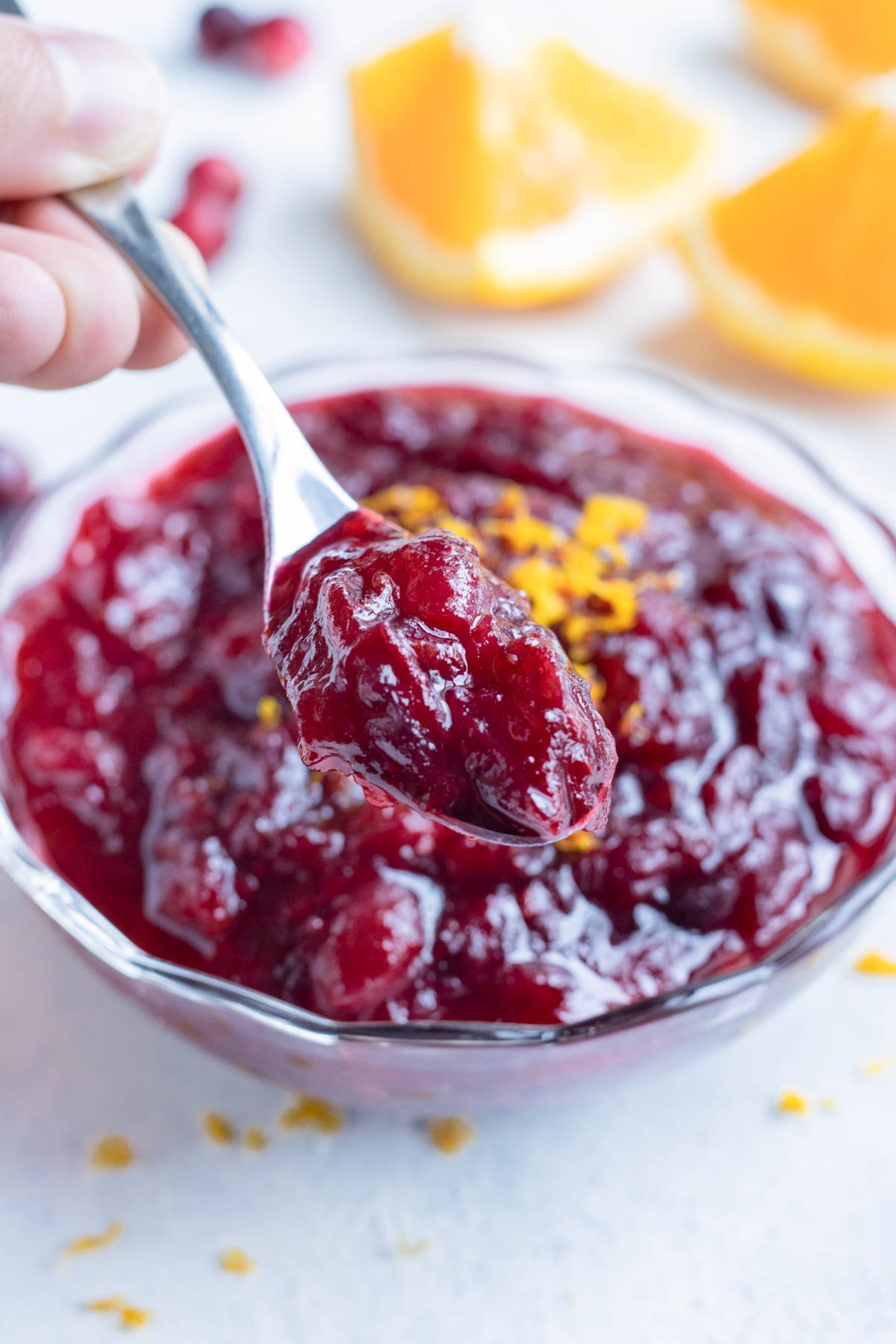 A spoon is lifted out of the bowl of cranberry sauce.