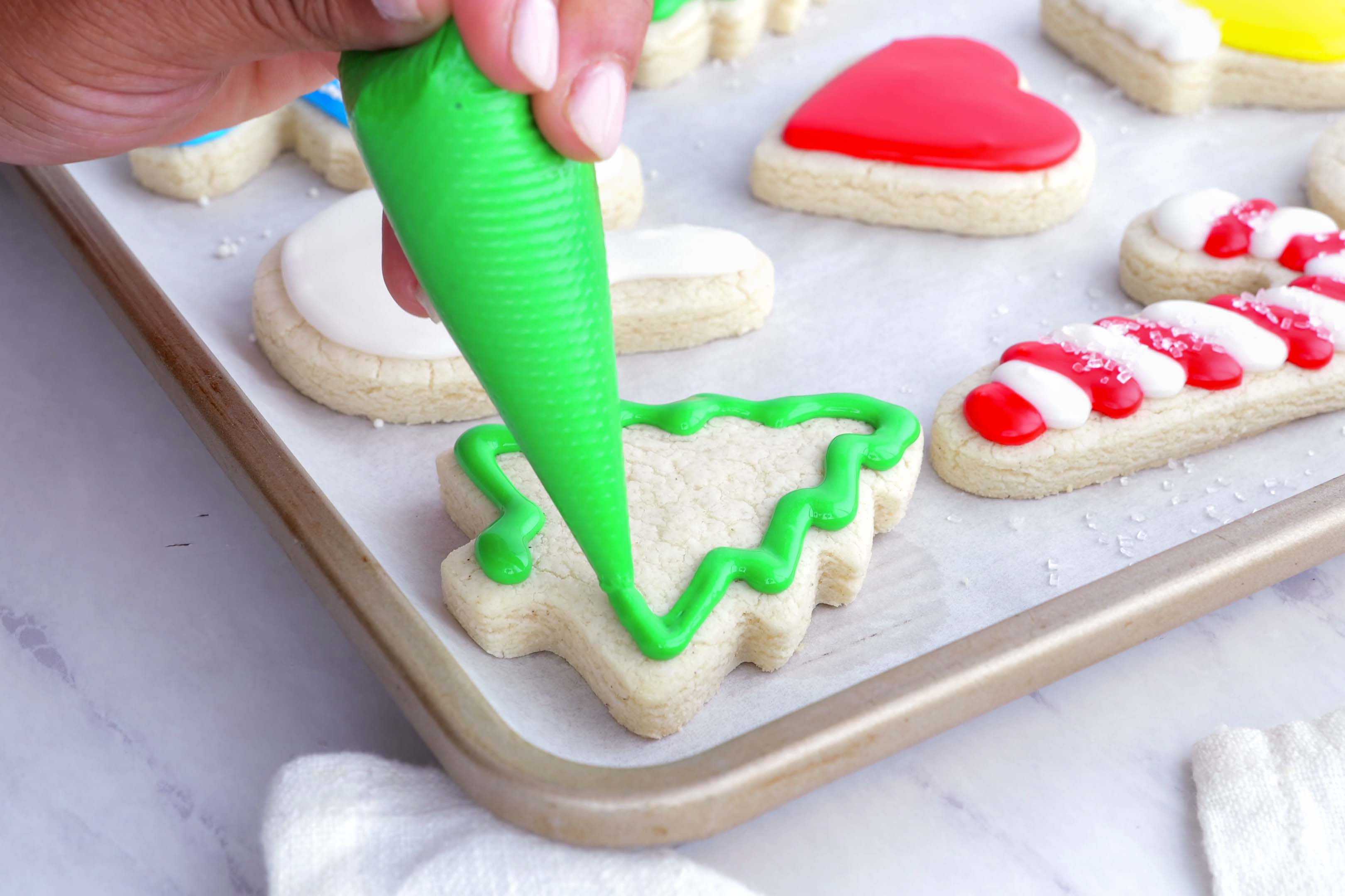 A hand pipes icing onto a cookie.