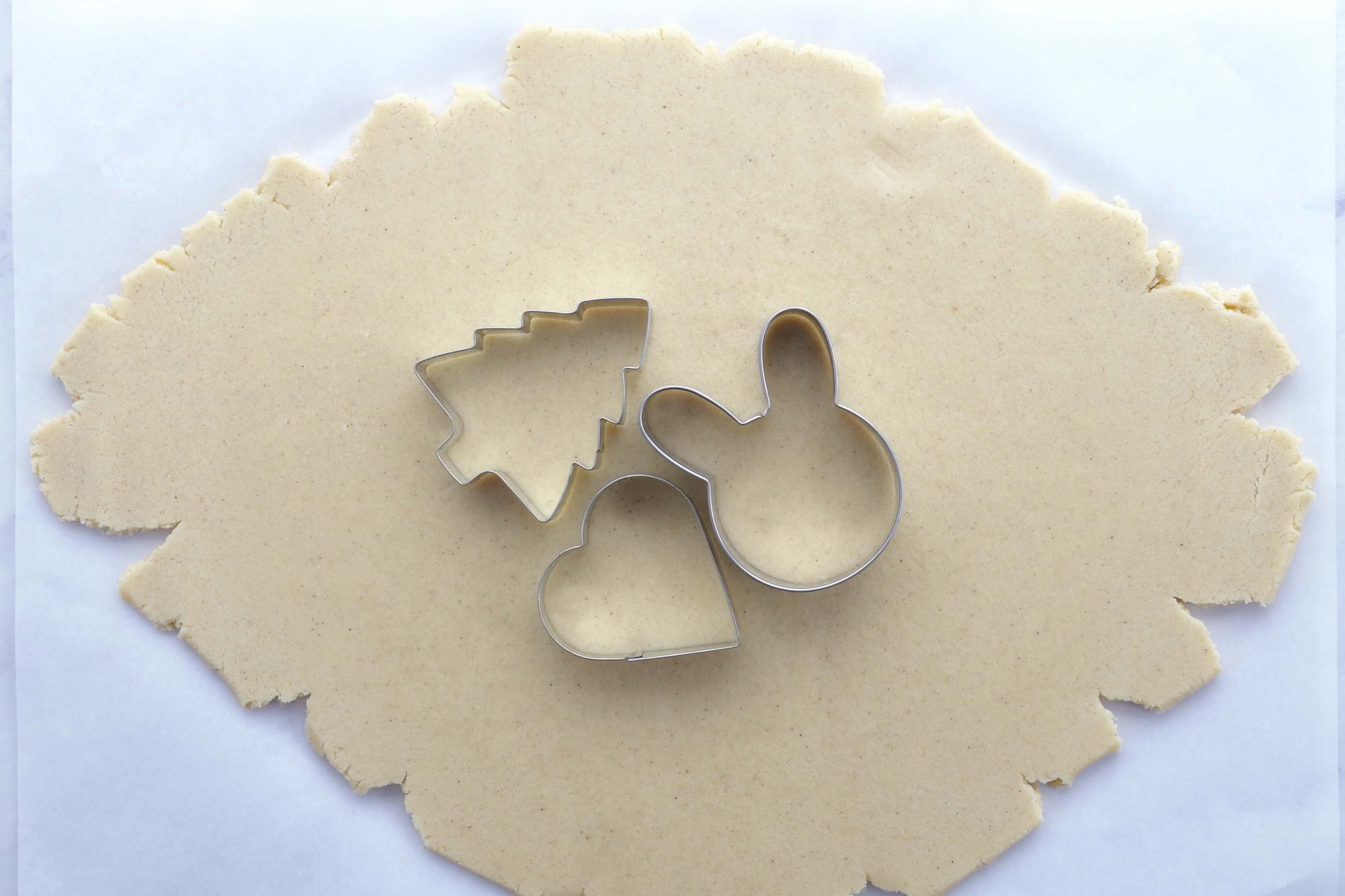 Cookie cutters are placed on a rolled out cookie dough.