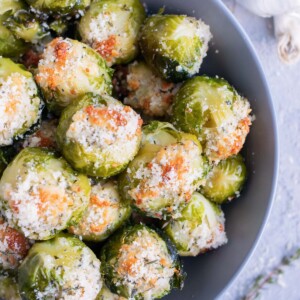 The best vegan crispy smashed Brussels sprouts with Parmesan cheese, garlic, and herbs in a grey bowl.