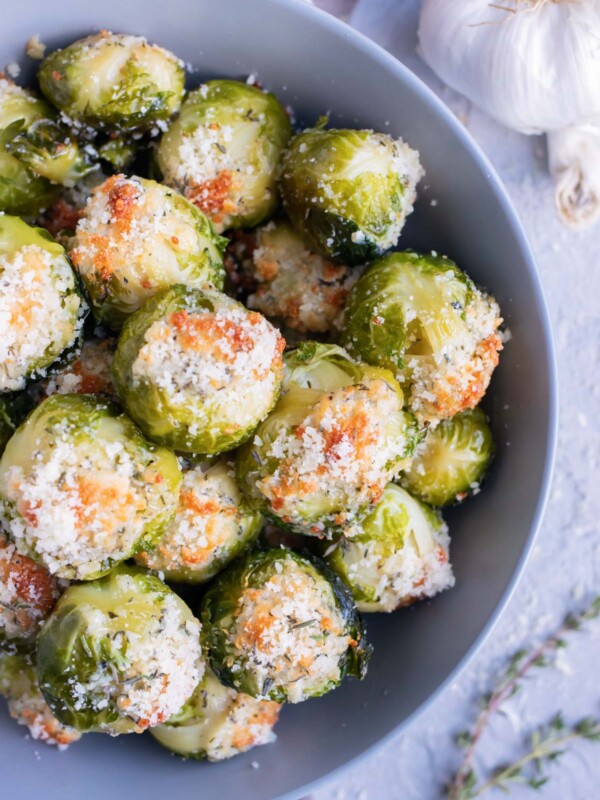 The best vegan crispy smashed Brussels sprouts with Parmesan cheese, garlic, and herbs in a grey bowl.