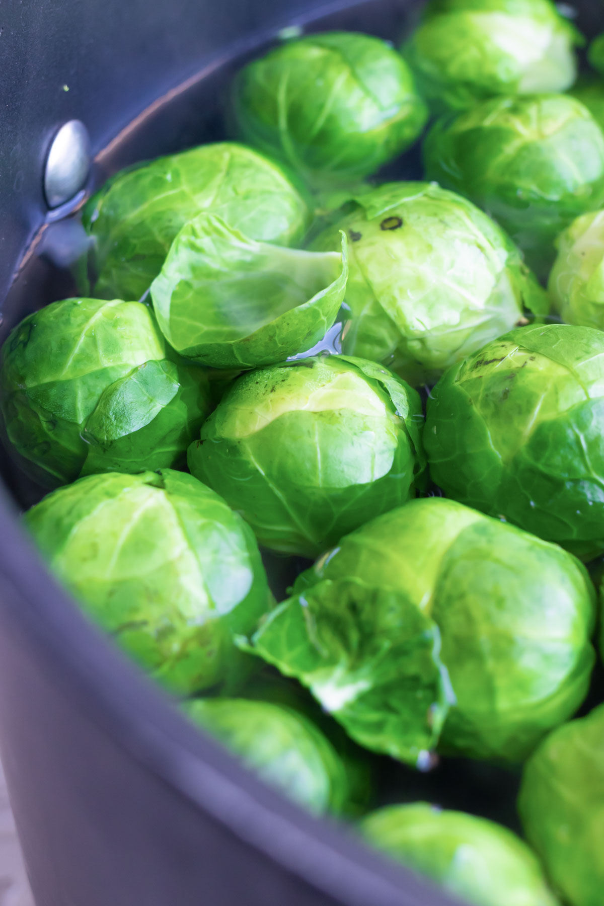 A pot of Brussels sprouts are boiled in water.