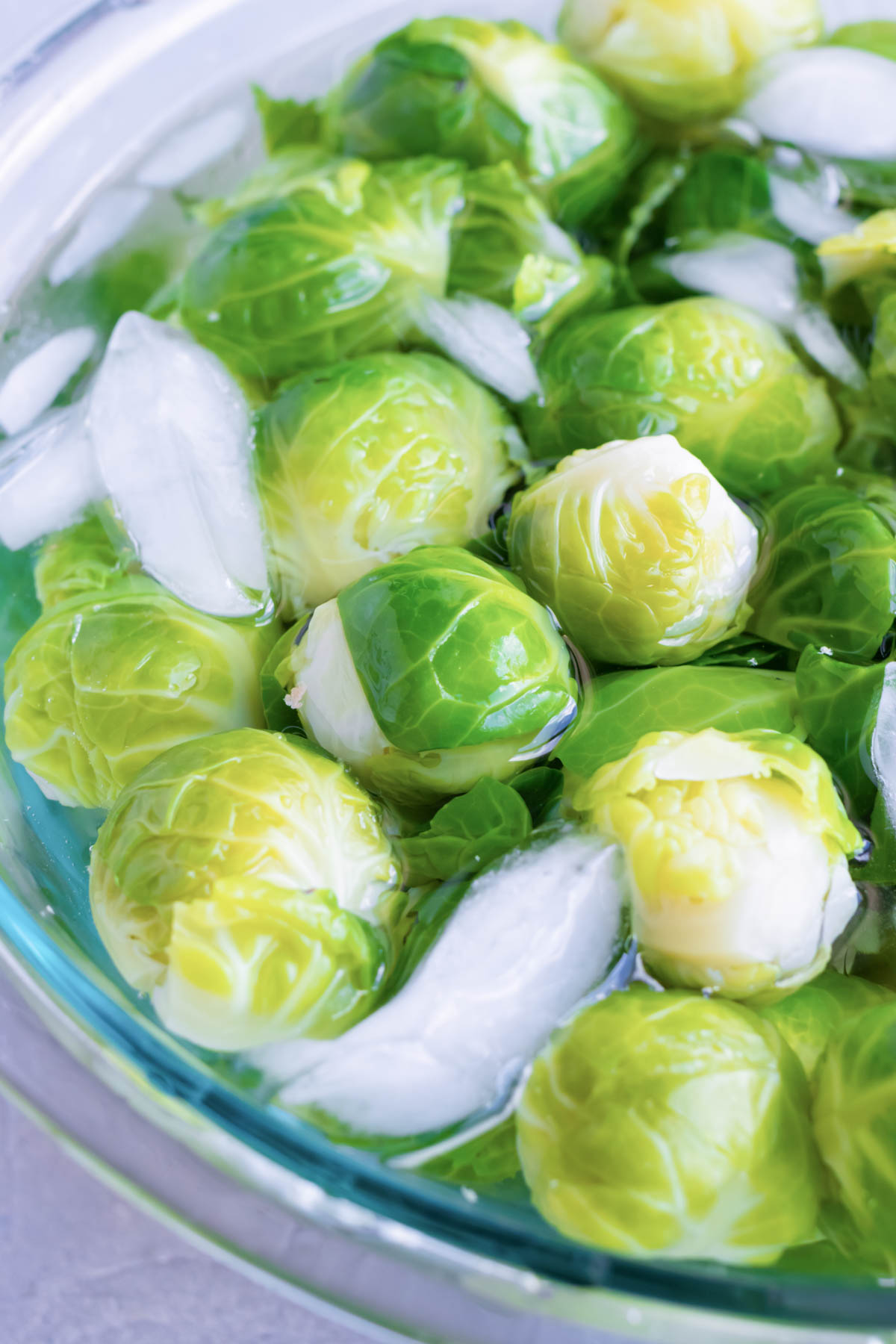 Boiled Brussels sprouts are added to a bowl of ice water.