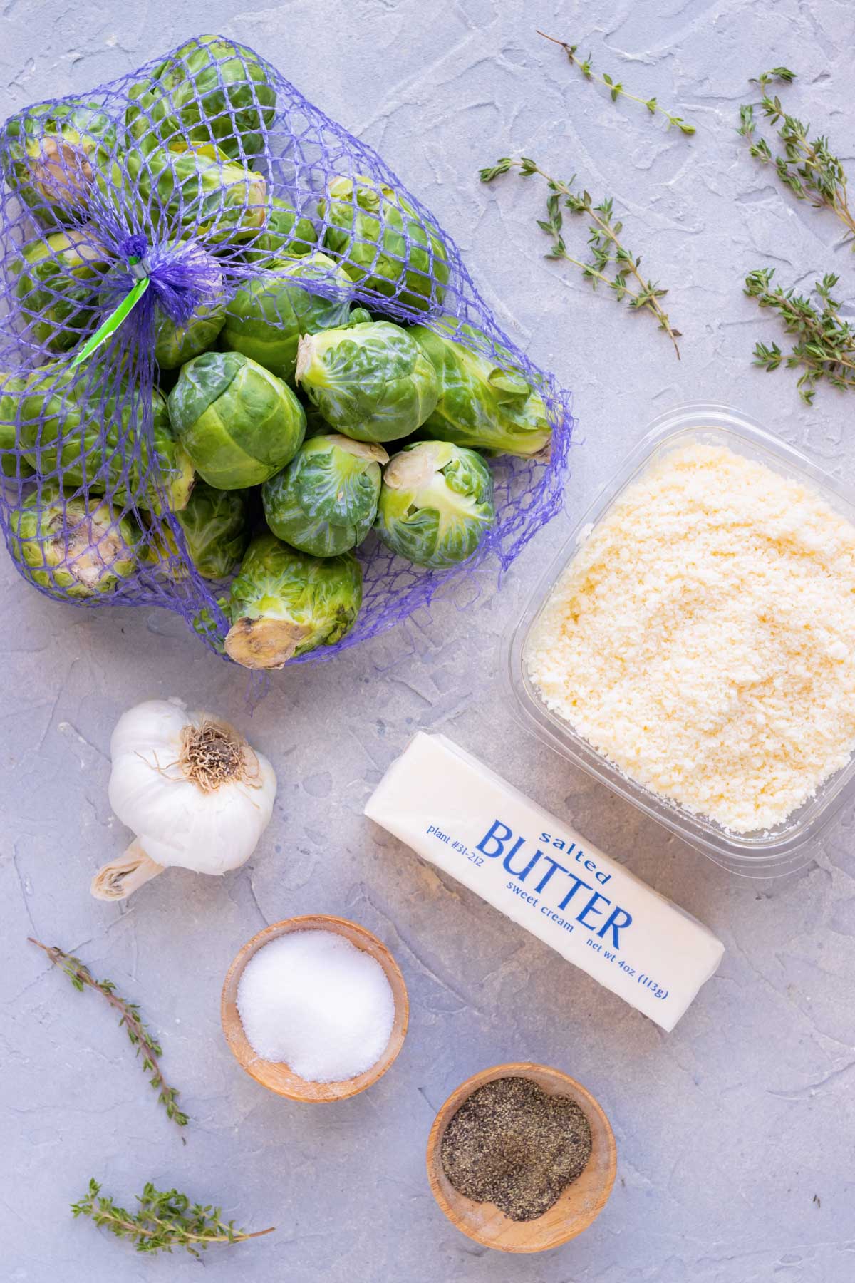 A one pound bag of Brussels sprouts, Parmesan cheese, butter, garlic, and herbs as the ingredients in a roasted Brussels sprouts recipe.