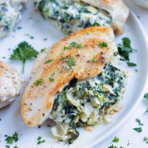 Chicken stuffed with a homemade spinach artichoke filling is served on a plate for dinner.