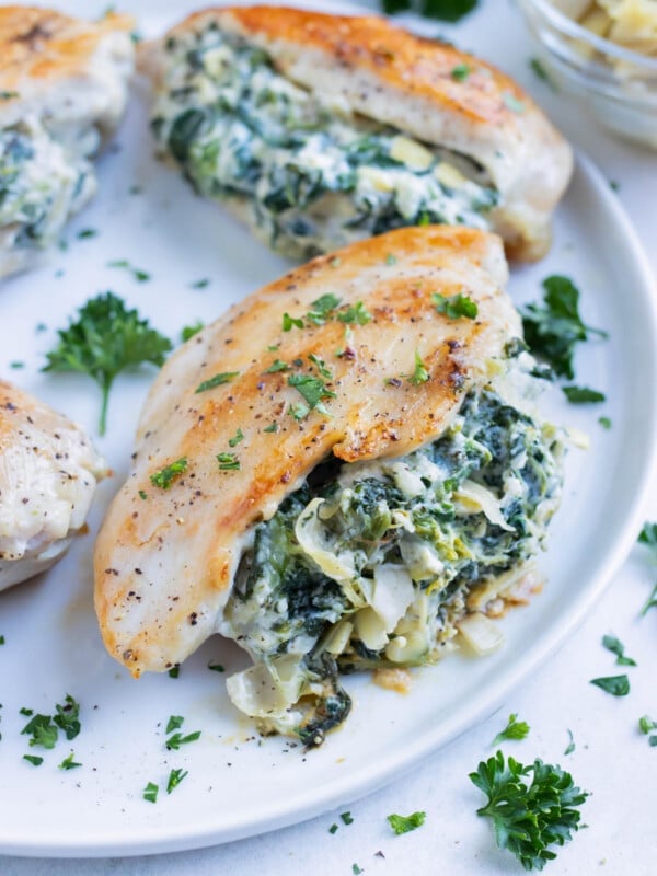 Chicken stuffed with a homemade spinach artichoke filling is served on a plate for dinner.