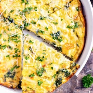 A slice of crustless quiche being picked up out of a baking dish.