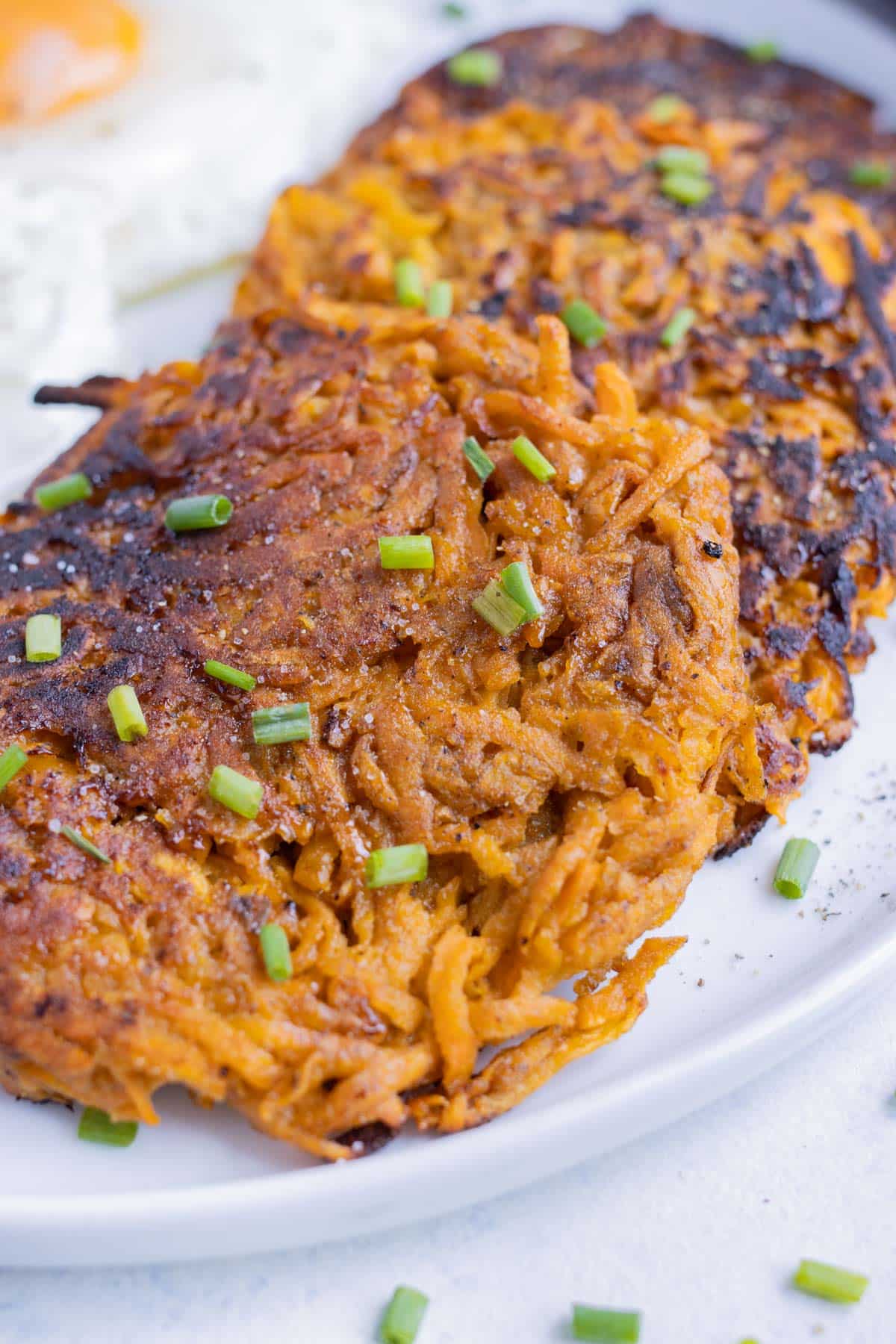 Hearty sweet potato hash browns are plated as a breakfast side.