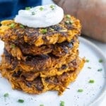 Four hash browns are plated and topped with sour cream and chives.