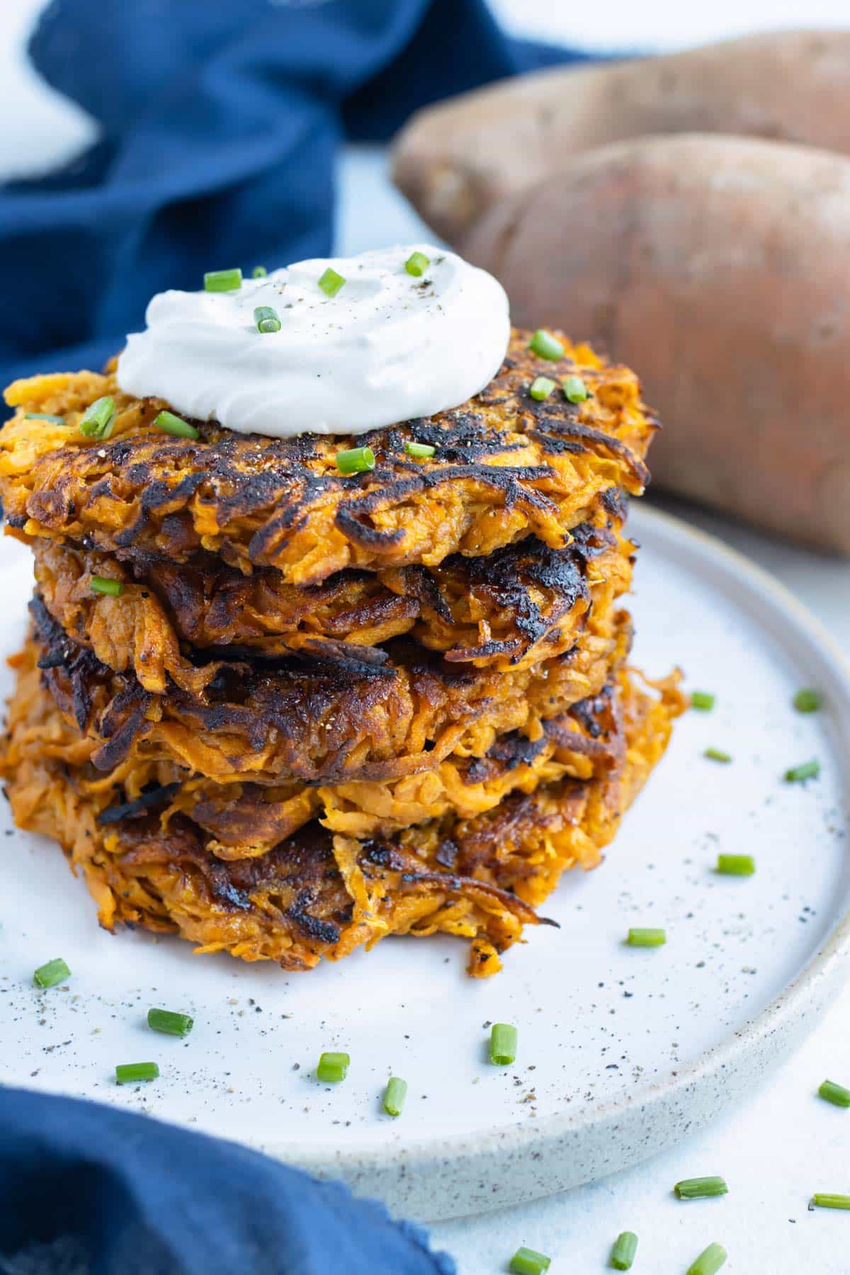 Four hash browns are plated and topped with sour cream and chives.