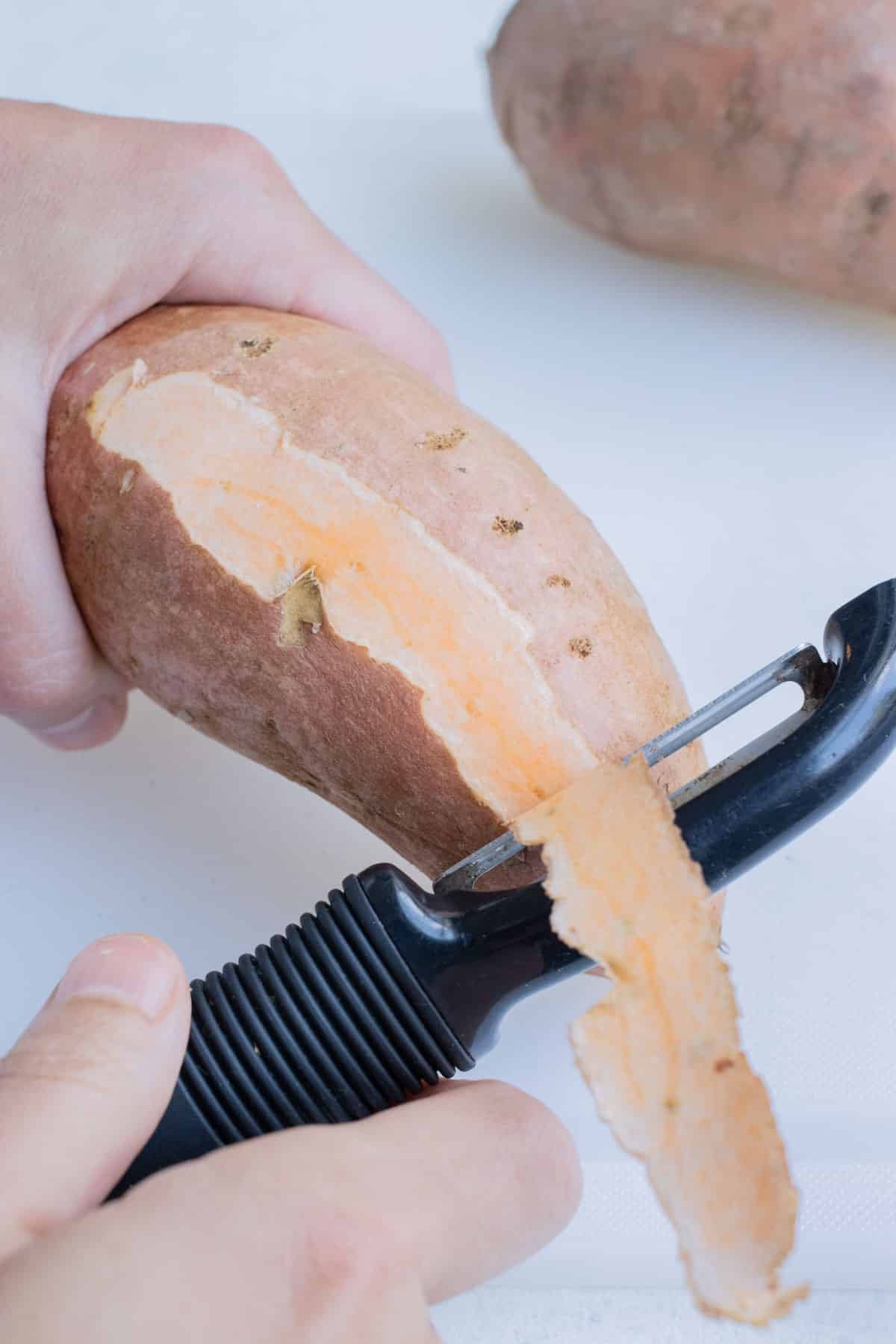 A vegetable peeler removes the skin from sweet potatoes for shredded sweet potato hash browns.