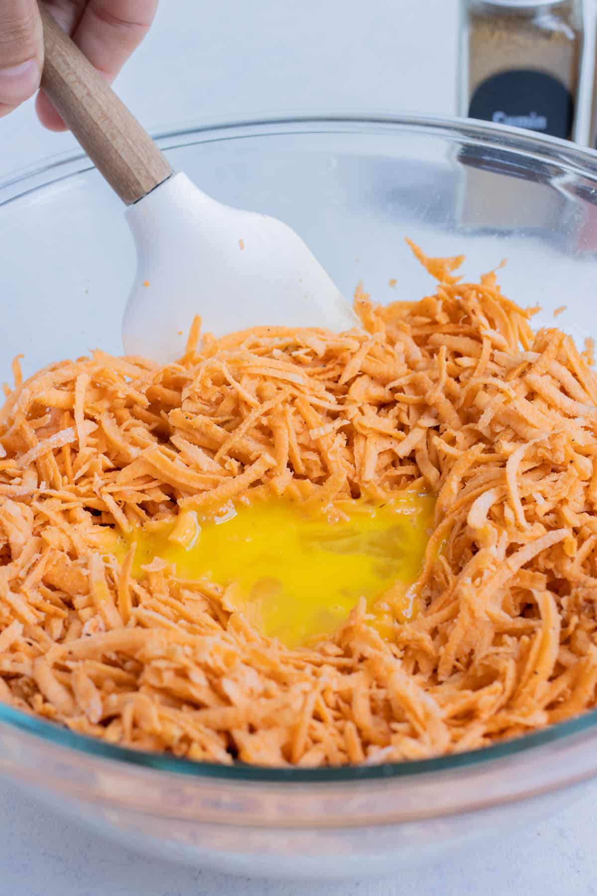 Egg is added to the grated sweet potatoes.