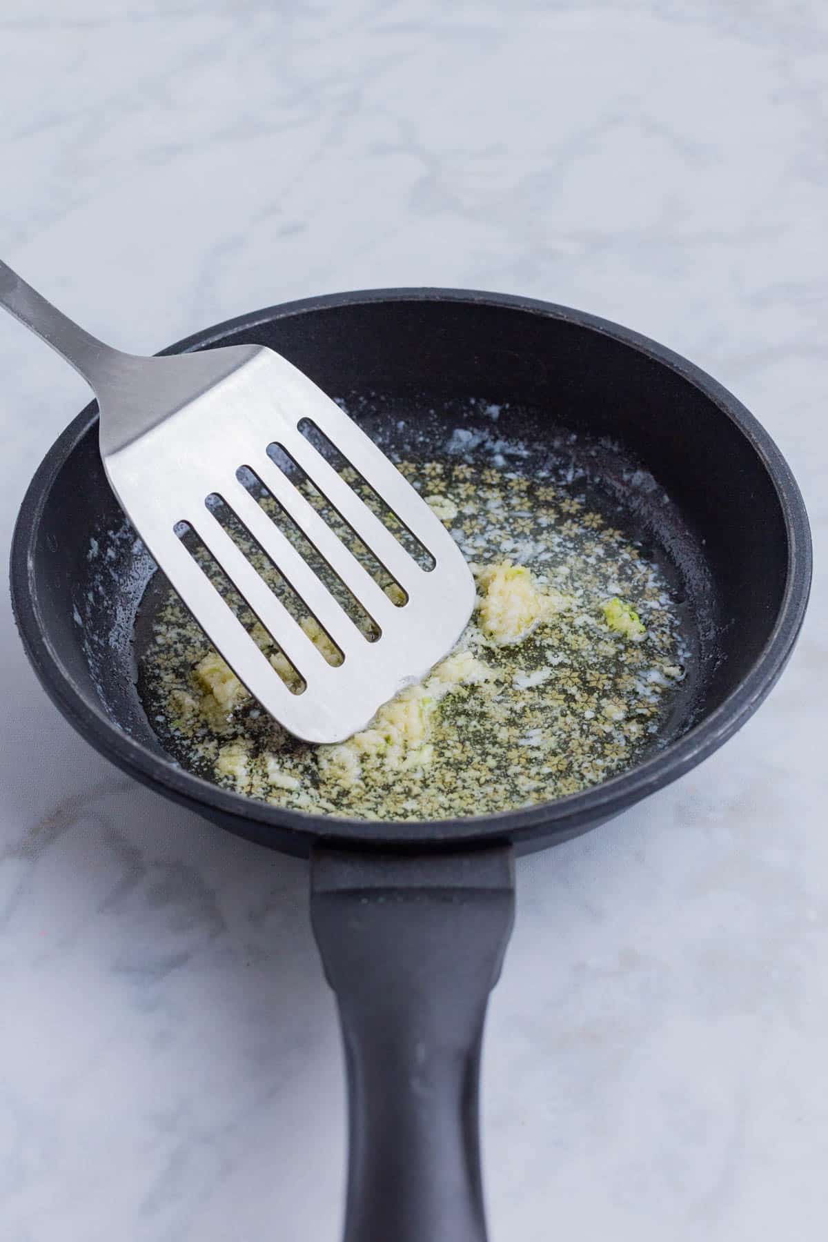 Garlic and butter are cooked together in a skillet.