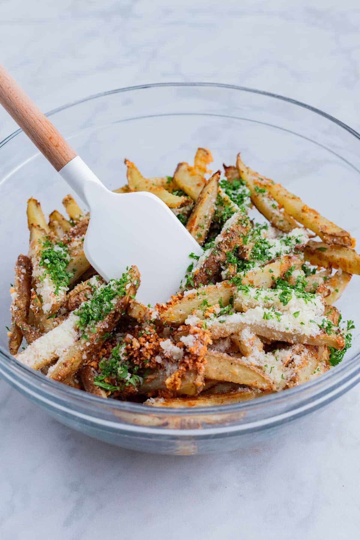 Parsley, Parmesan cheese, and seasonings are added to the baked fries.