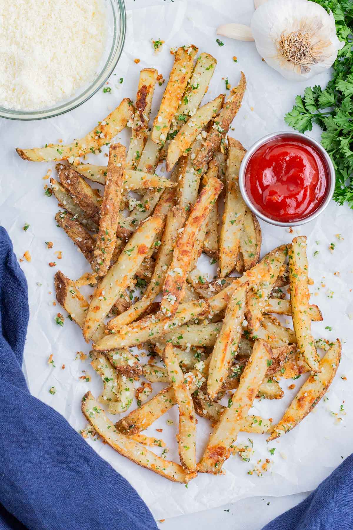 Parmesan garlic fries are served on a white tray with ketchup.