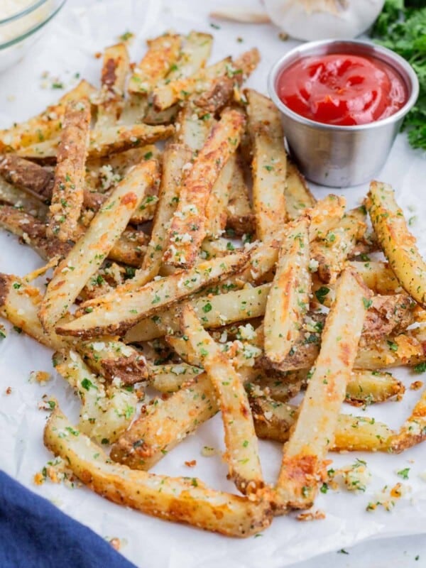 Parmesan garlic fries are served on a white tray with ketchup.