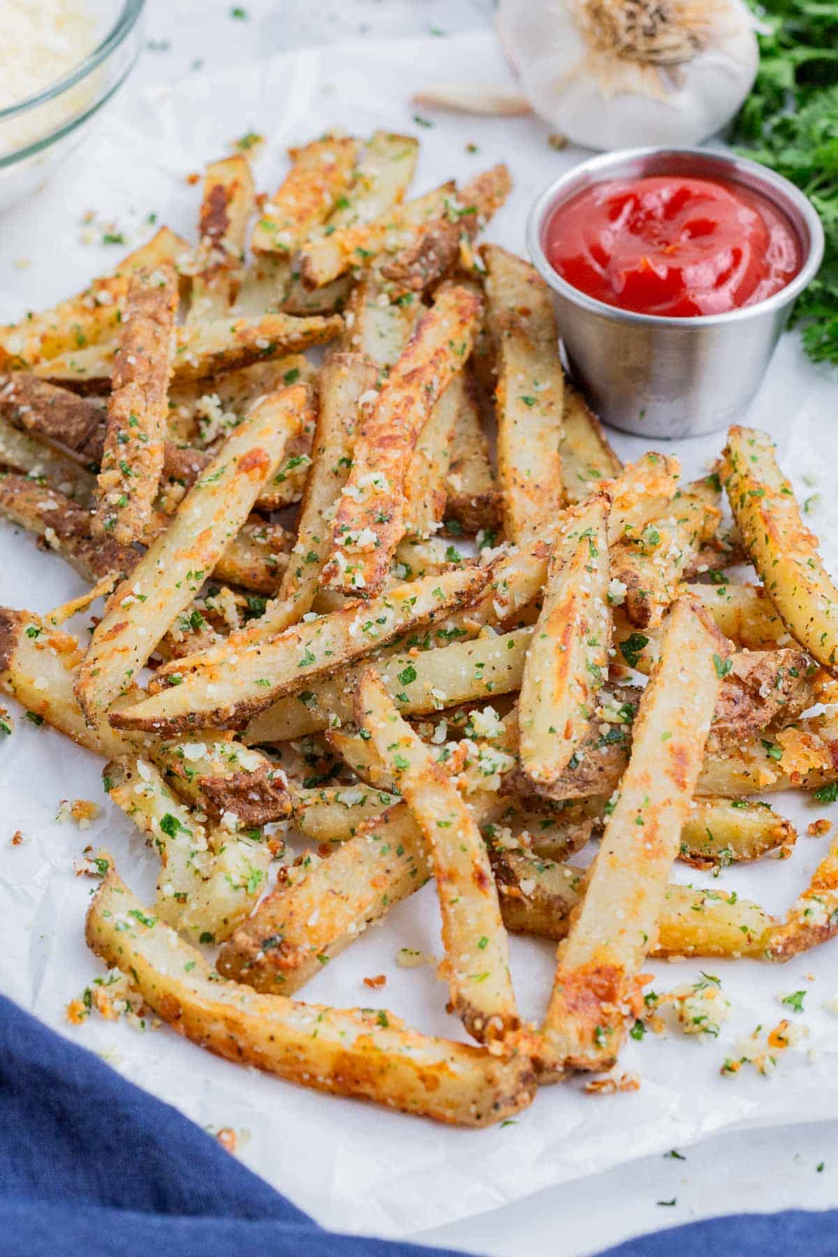 Parmesan garlic fries are served on a white tray with ketchup.