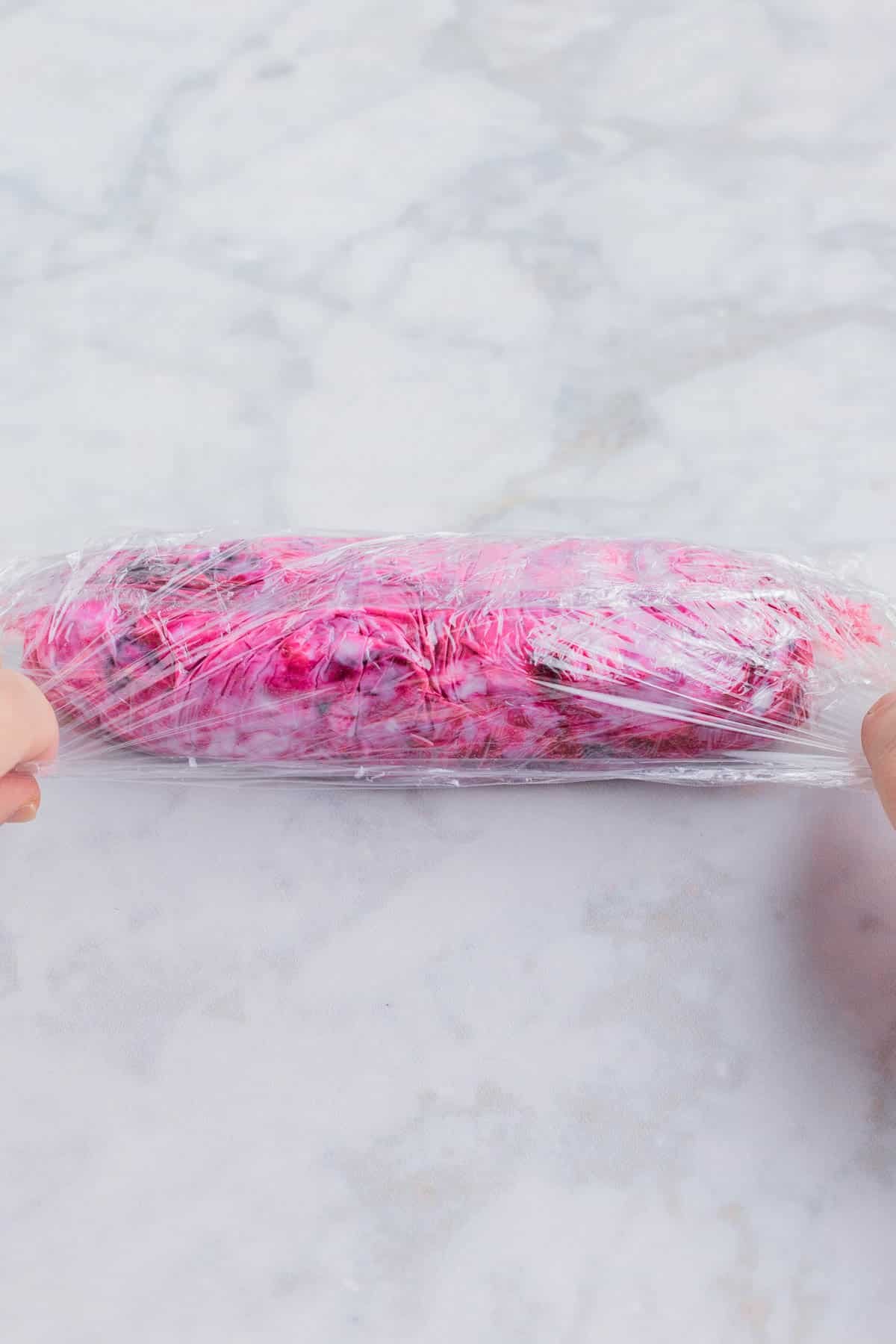 A blueberry goat cheese log is wrapped and shaped in plastic.