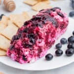 Blueberry goat cheese is served alongside crackers on a white plate.