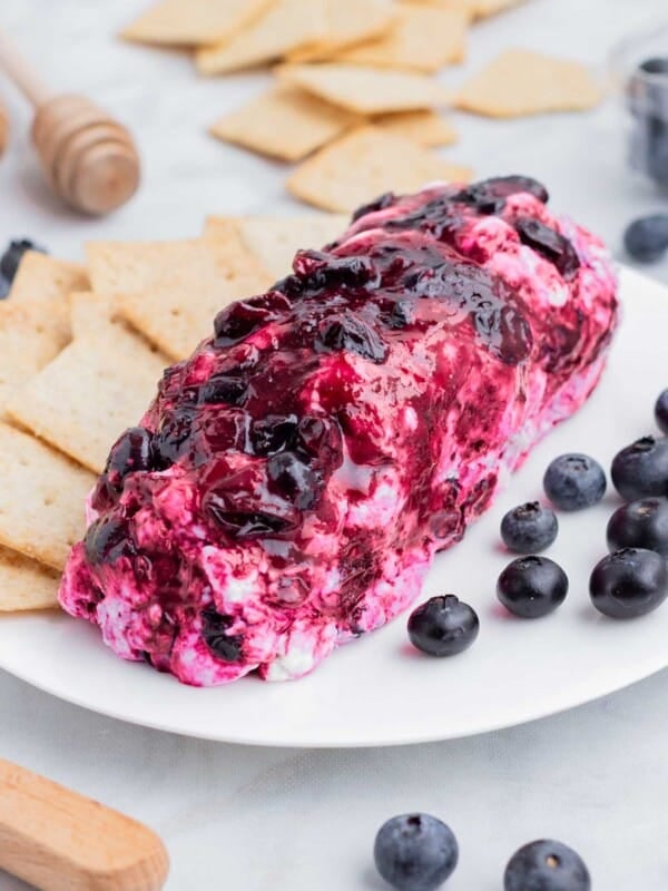 Blueberry goat cheese is served alongside crackers on a white plate.