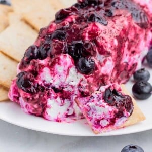 Blueberry goat cheese is served alongside crackers on a white plate.
