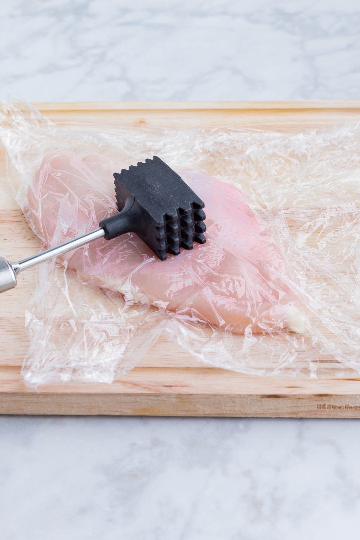 Chicken is pounded thin with a meat mallet.