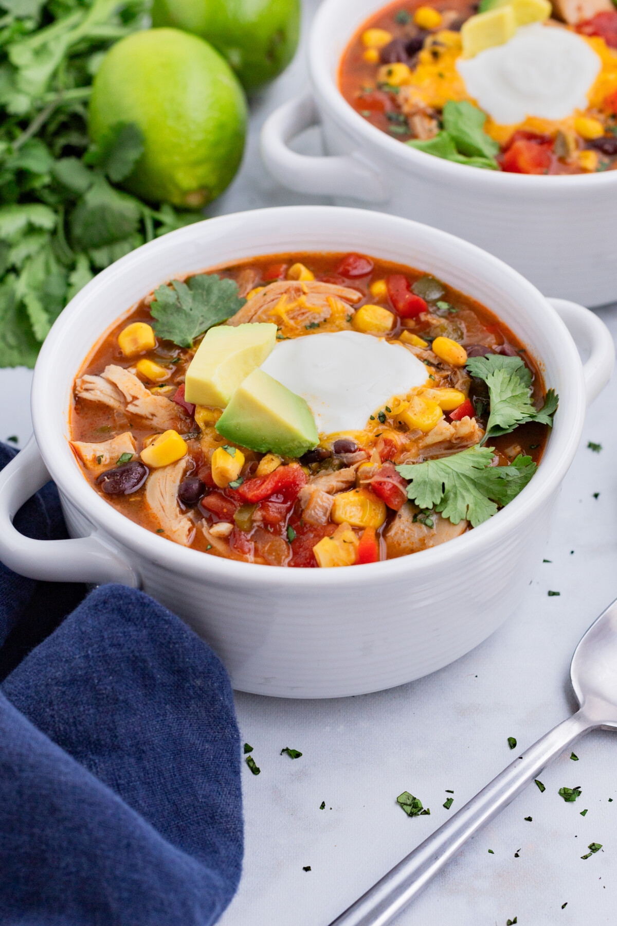 Two white soup bowls are full of a chicken enchilada soup recipe.