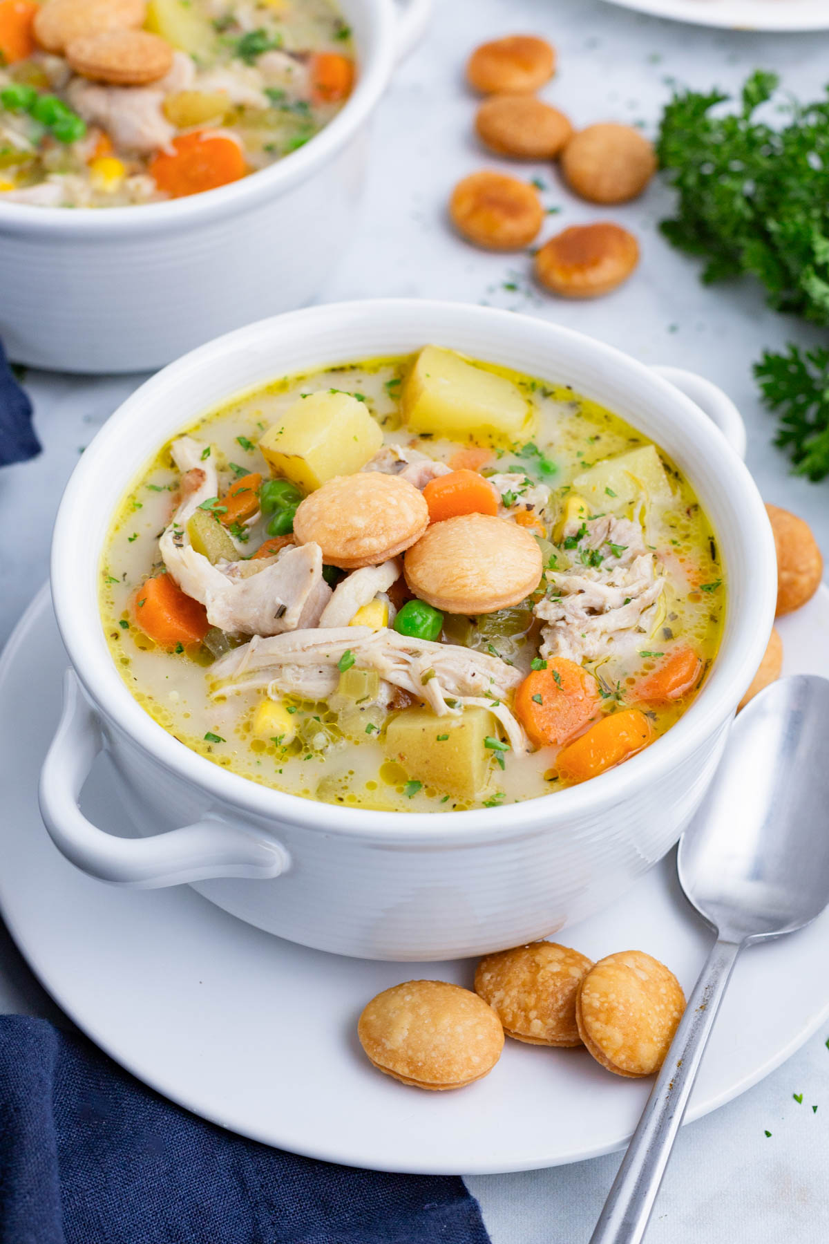 A healthy chicken pot pie soup recipe is served in a white bowl.