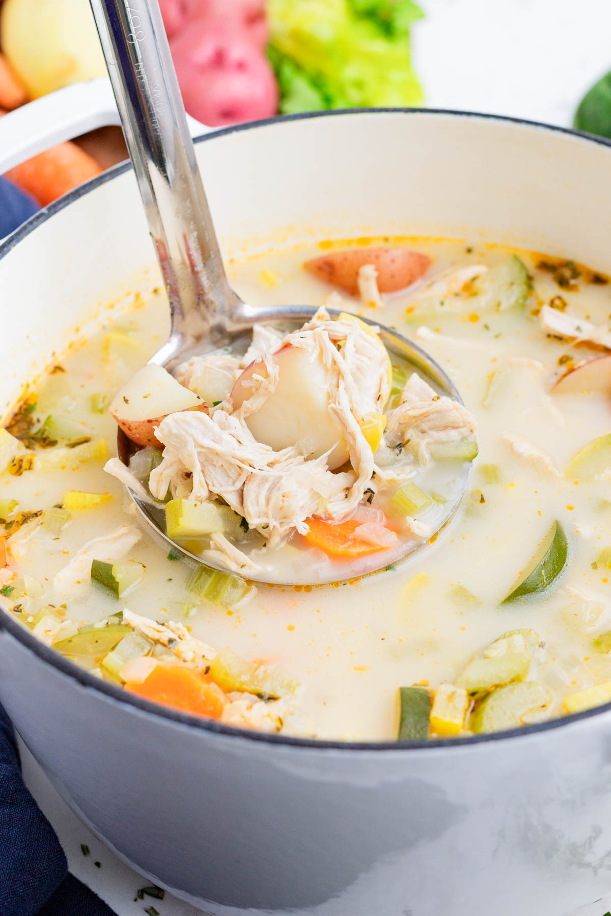 A healthy chicken vegetable soup recipe being scooped out of a pot.