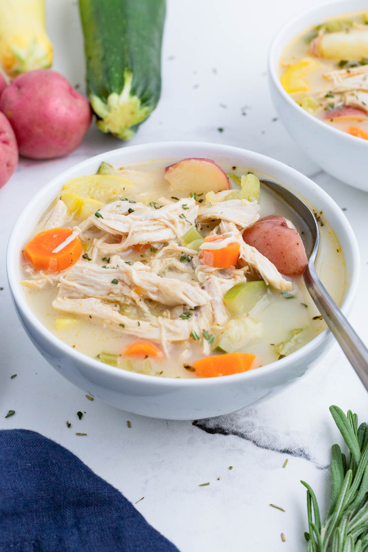 Chicken soup with healthy veggies is served in a white bowl.