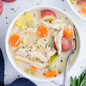 A white bowl full of a hearty chicken vegetable soup.