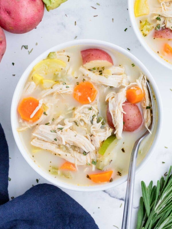 A white bowl full of a hearty chicken vegetable soup.