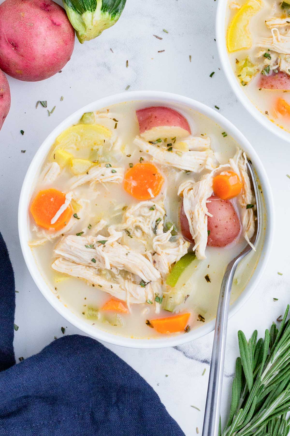 A white bowl full of a hearty chicken vegetable soup.