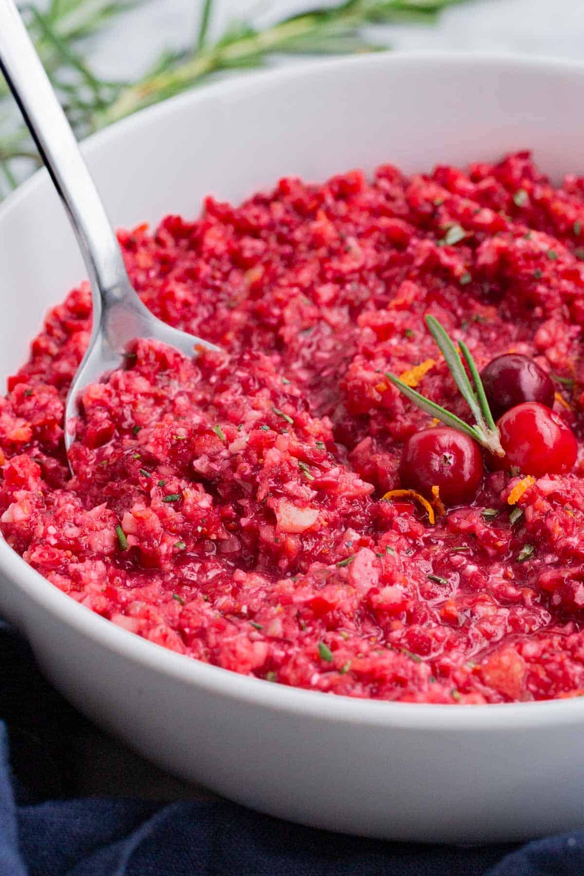 A metal spoon is used to serve this orange cranberry relish.