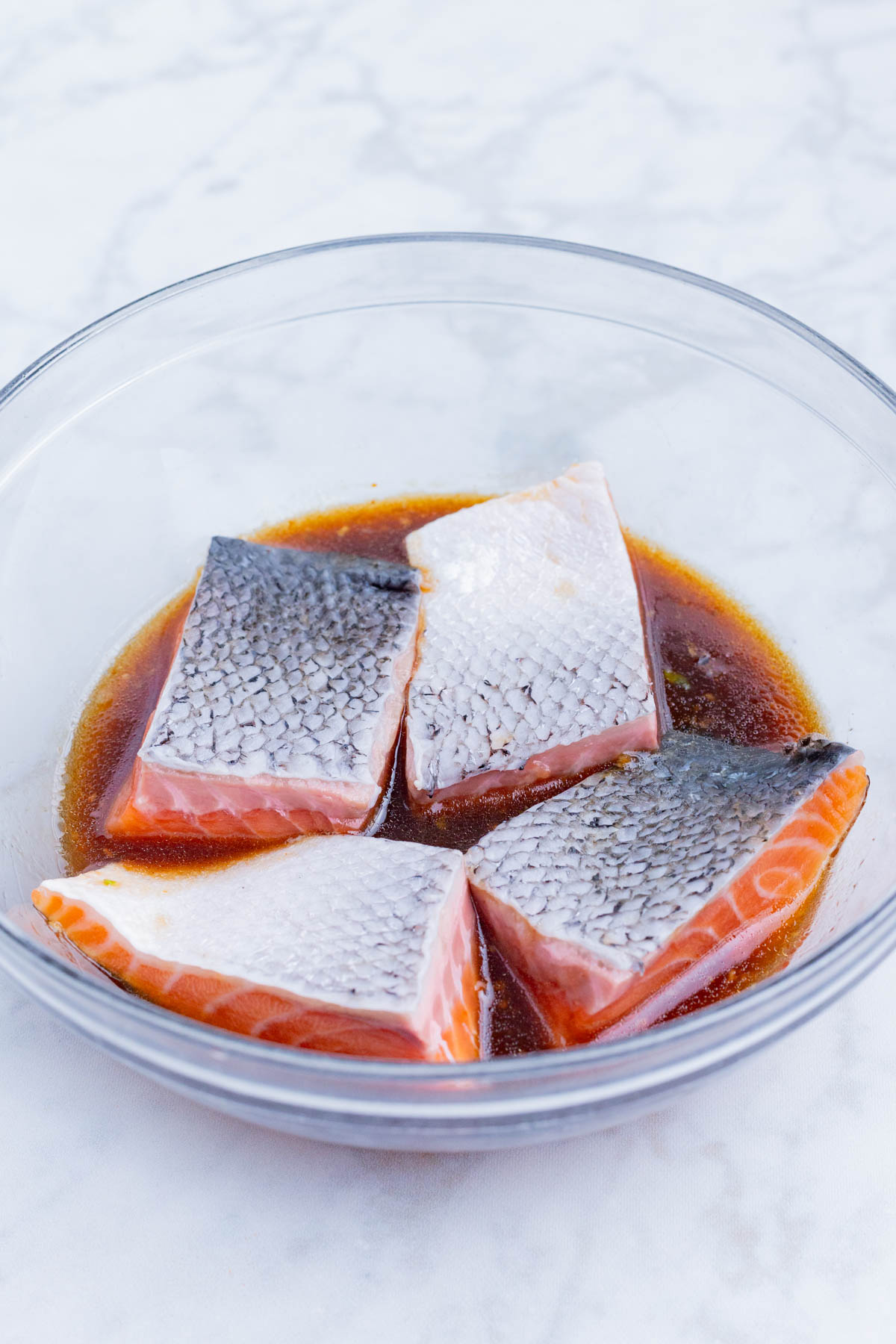 Salmon fillets are marinated in a bowl of honey sriracha sauce.