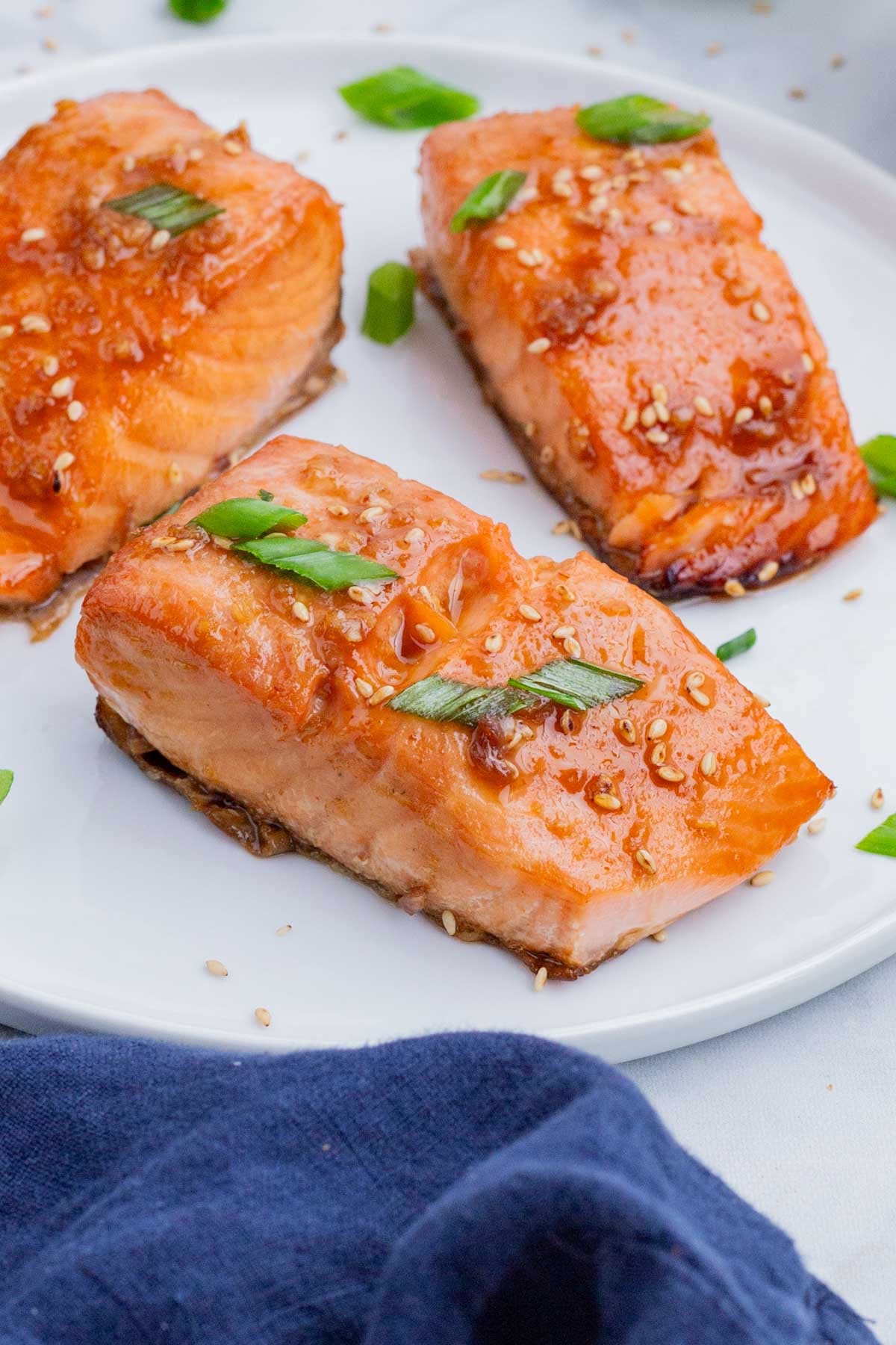 Honey Sriracha Glazed Salmon RECIPE plated with green onion garnish.