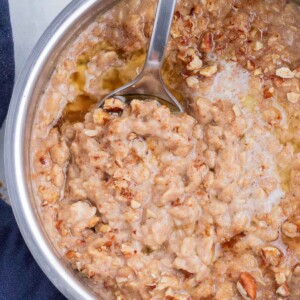 Oatmeal is cooked in a pot and flavored with maple syrup and brown sugar.