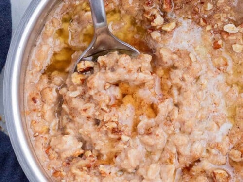 Oatmeal is cooked in a pot and flavored with maple syrup and brown sugar.