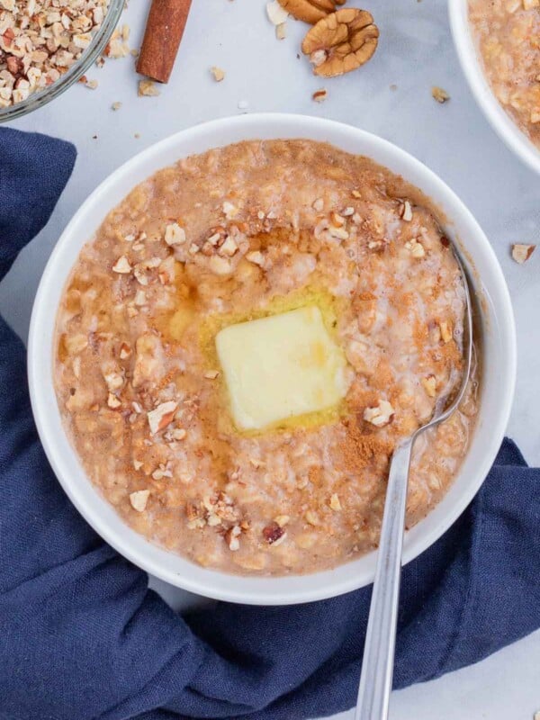 A spoon stirs butter into a bowl of oatmeal.