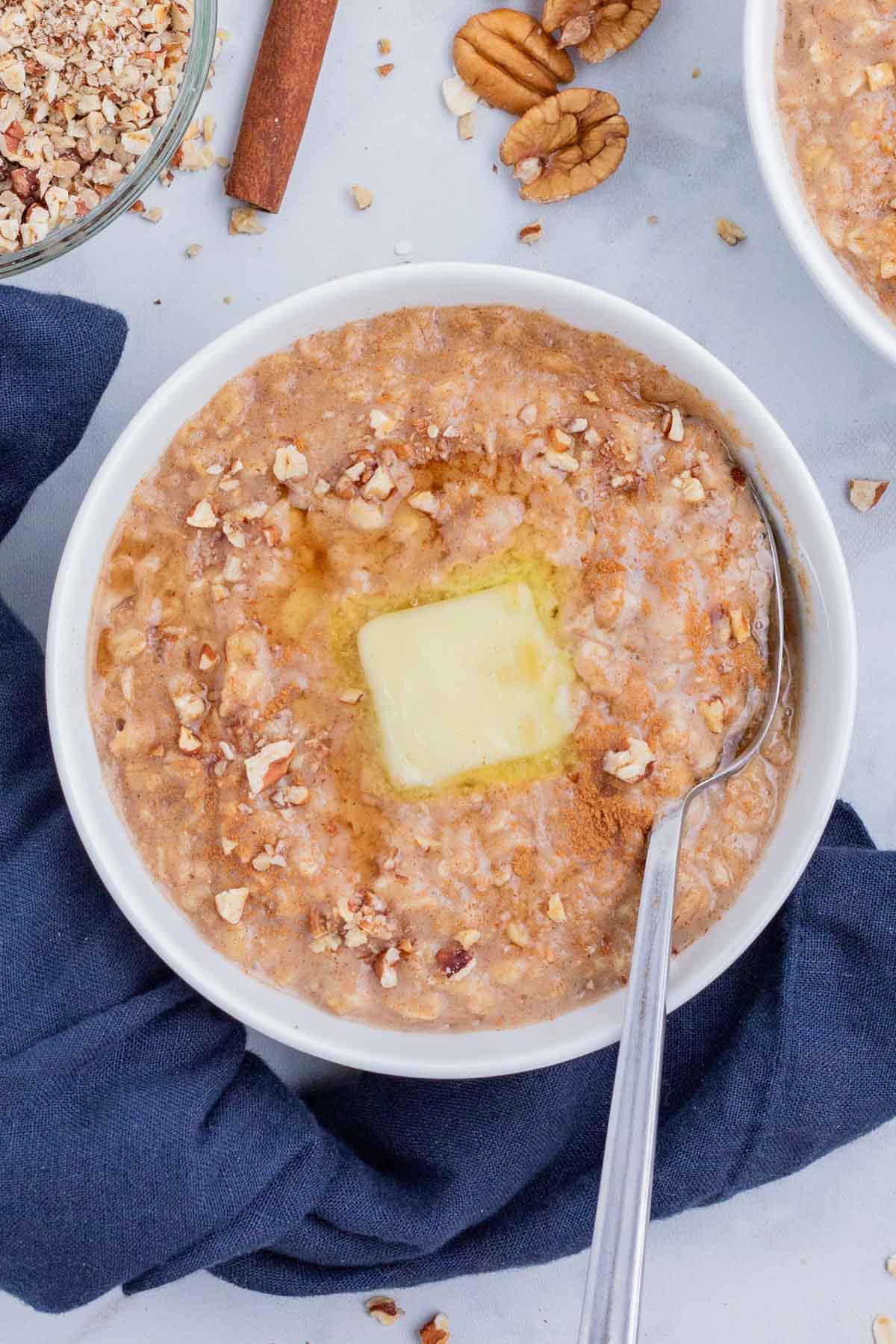 A spoon stirs butter into a bowl of oatmeal.