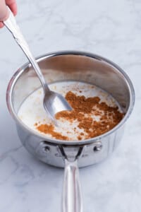 Oats, milk, and syrup, and cinnamon are added to a saucepan for a maple brown sugar oatmeal recipe.
