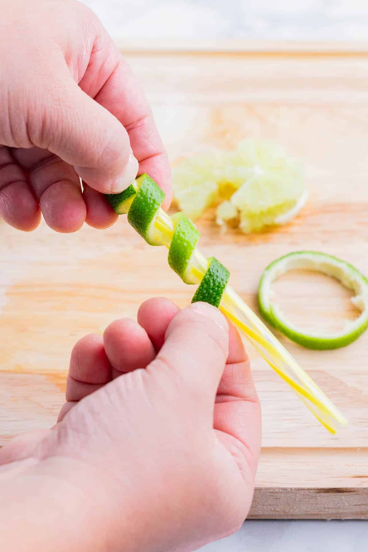 A lime peel is wrapped around a straw for garnish.