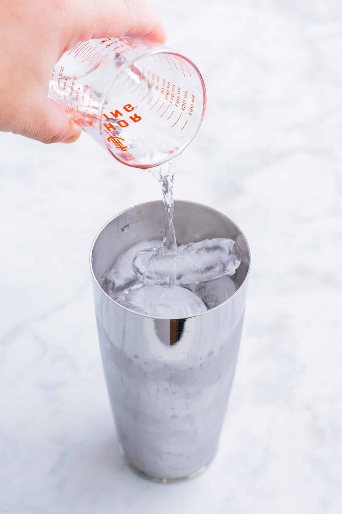 Tequila is added to a shaker with ice.