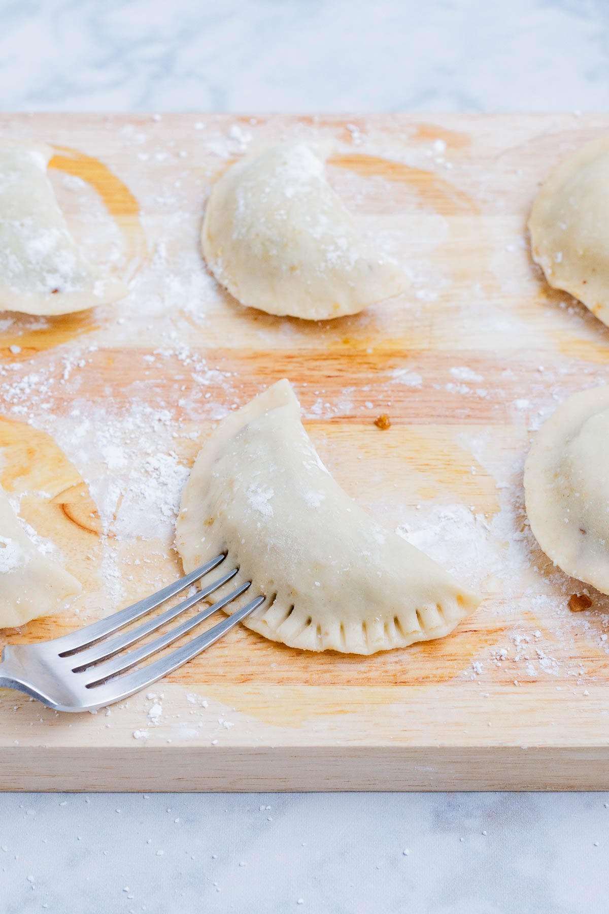 A fork crimps the edges of the hand pie to seal it.