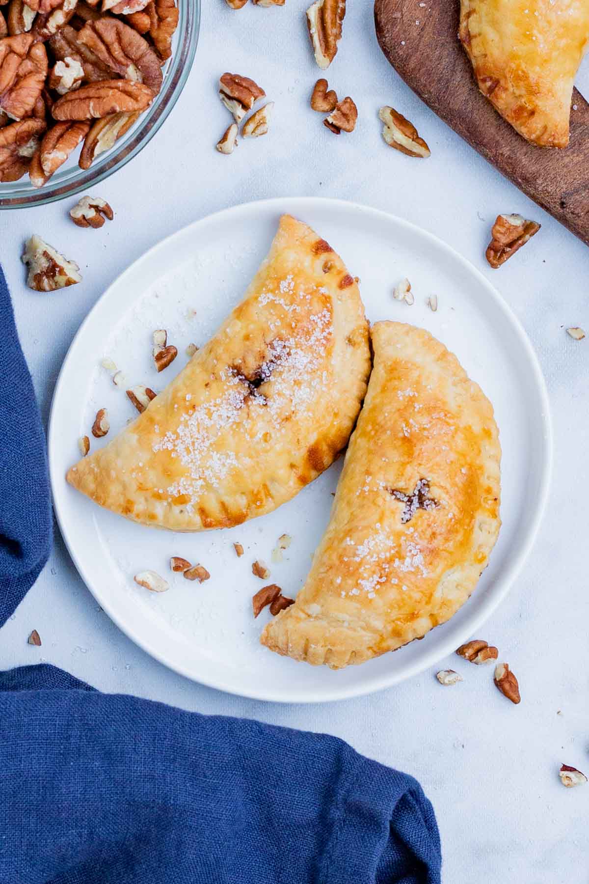 Two pecan hand pies sit on a plate to be served.