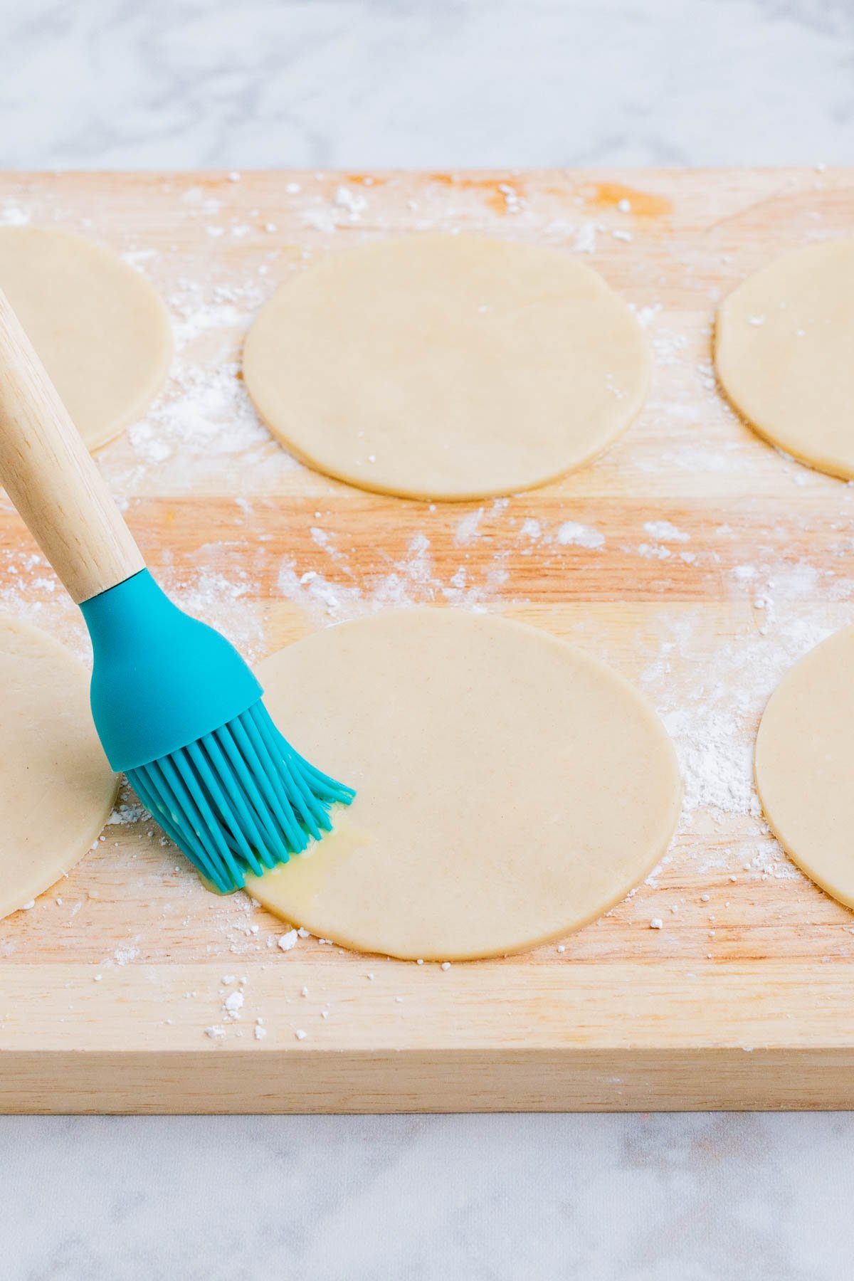 Egg wash is brushed on the edges of the pie crust.