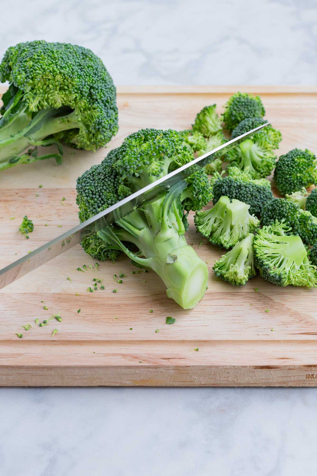 Broccoli is chopped into smaller florets to be roasted in the oven.