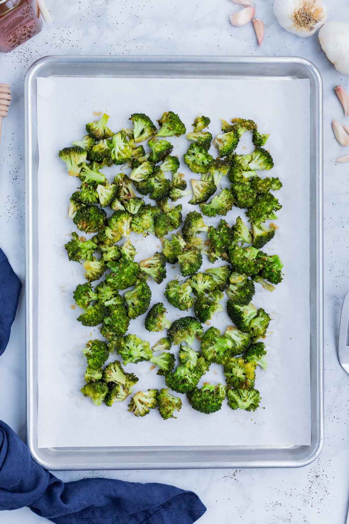 Seasoned broccoli is roasted on a baking sheet.